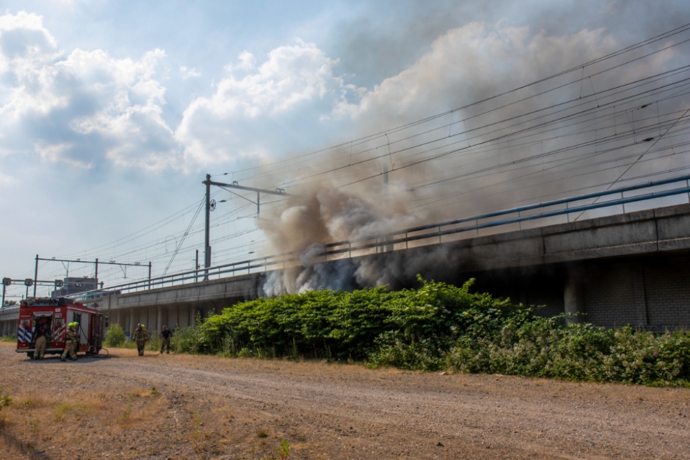 Flinke rookwolken bij brand onder spoorviaduct aan de Horvathweg