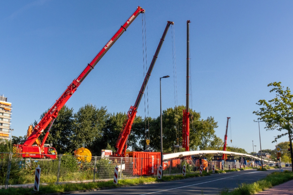 Met behulp van de kranen wordt de leiding de grond in getrokken