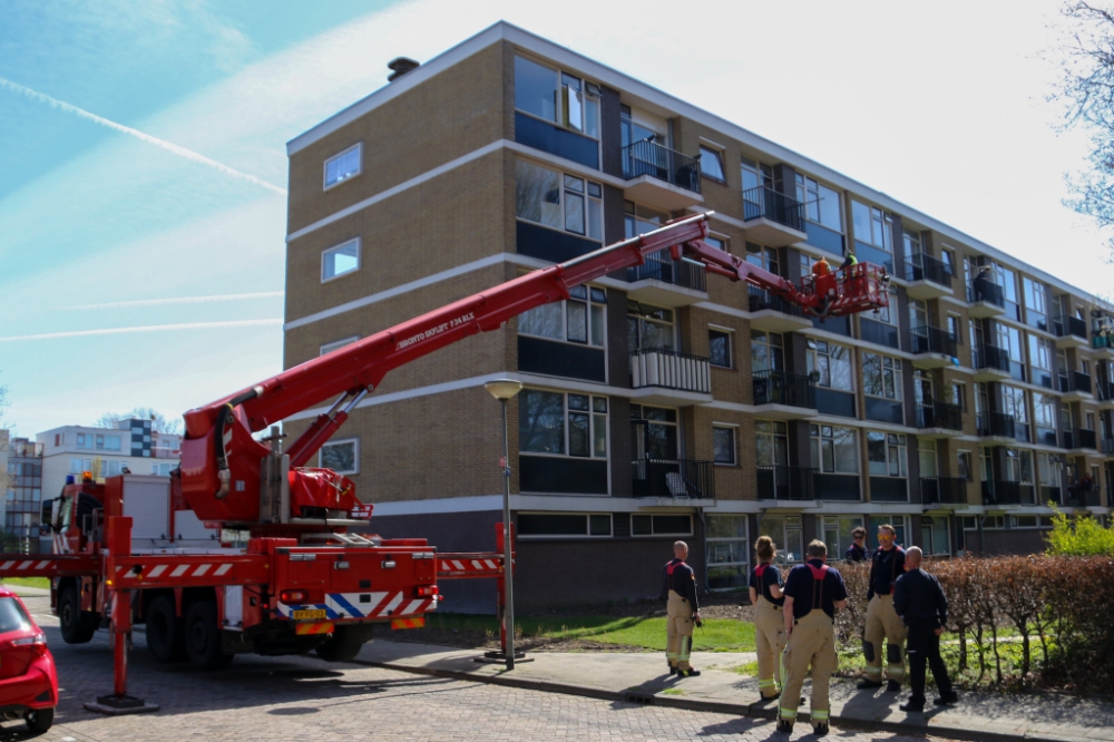 Brandweer helpt man die vastzit op balkon