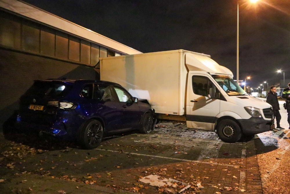Auto vliegt uit de bocht en ramt muur en bakwagens