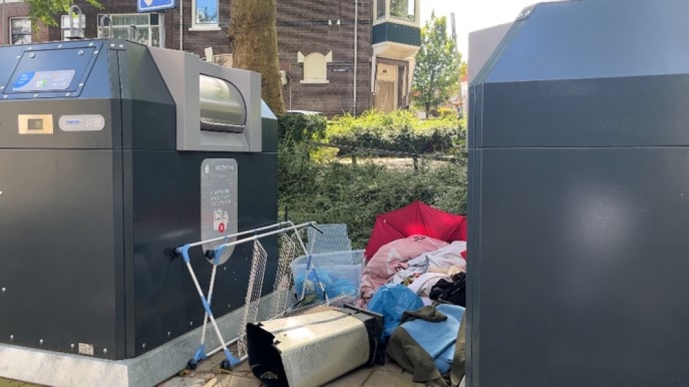 Een container waar veel bijgeplaatst afval bij staat