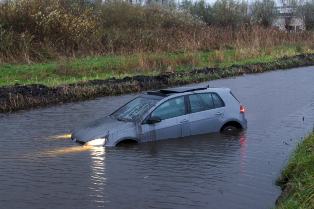 Auto te water op de Woudweg